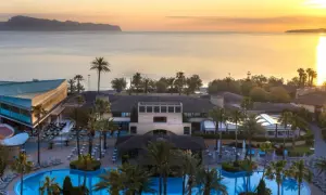 Resortanlage mit Pool und Meerblick bei Sonnenuntergang.