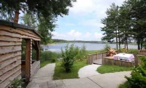 Holzhütte mit Blick auf den Senftenberger See, Tisch mit Blumen und Sonnenblumen.