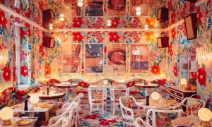 Ein Restaurant mit floralem Muster an Wänden, Boden und Möbeln, Tische sind gedeckt.