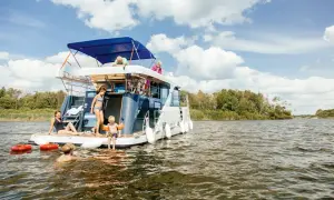 Familie auf einem Hausboot in der Mecklenburgischen Seenplatte, einige schwimmen, andere entspannen sich.