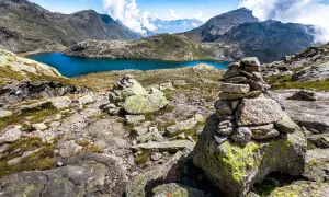 Bergsee mit türkisfarbenem Wasser, umgeben von felsiger Landschaft und Gipfeln.