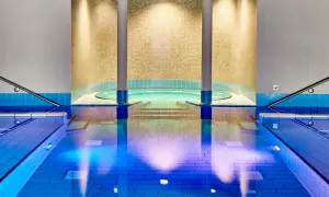 Innenpool mit Whirlpool und blauen Fliesen, beleuchtet.