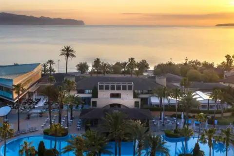 Resortanlage mit Pool und Meerblick bei Sonnenuntergang.