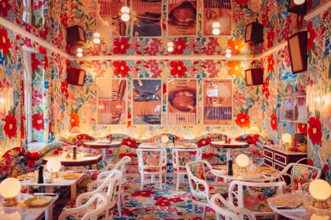 Ein Restaurant mit floralem Muster an Wänden, Boden und Möbeln, Tische sind gedeckt.