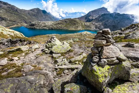 Bergsee mit türkisfarbenem Wasser, umgeben von felsiger Landschaft und Gipfeln.