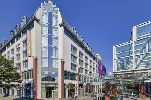 Mercure Hotel Berlin Tempelhof: moderne Fassade mit Glas und Ziegelsteinen, Flagge und Eingangsbereich.