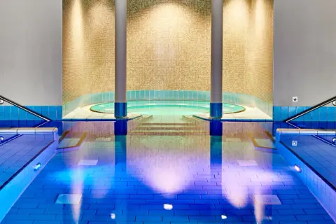 Innenpool mit Whirlpool und blauen Fliesen, beleuchtet.