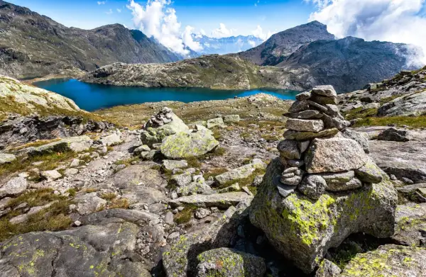 Bergsee mit türkisfarbenem Wasser, umgeben von felsiger Landschaft und Gipfeln.