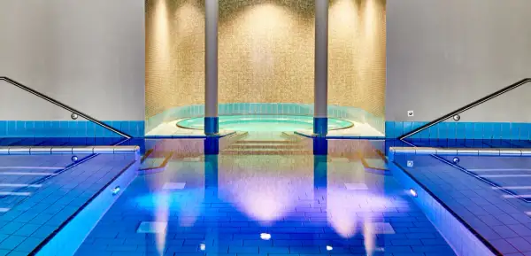 Innenpool mit Whirlpool und blauen Fliesen, beleuchtet.